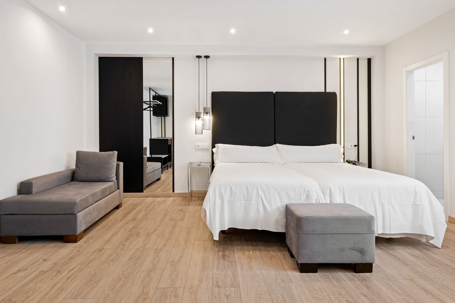 Un dormitorio moderno con una cama grande, un sofá y un reposapiés.