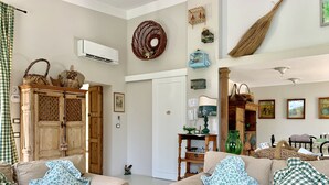 Una sala de estar con dos sofás color beige, un mueble de madera, una cesta de mimbre y un jarrón verde.