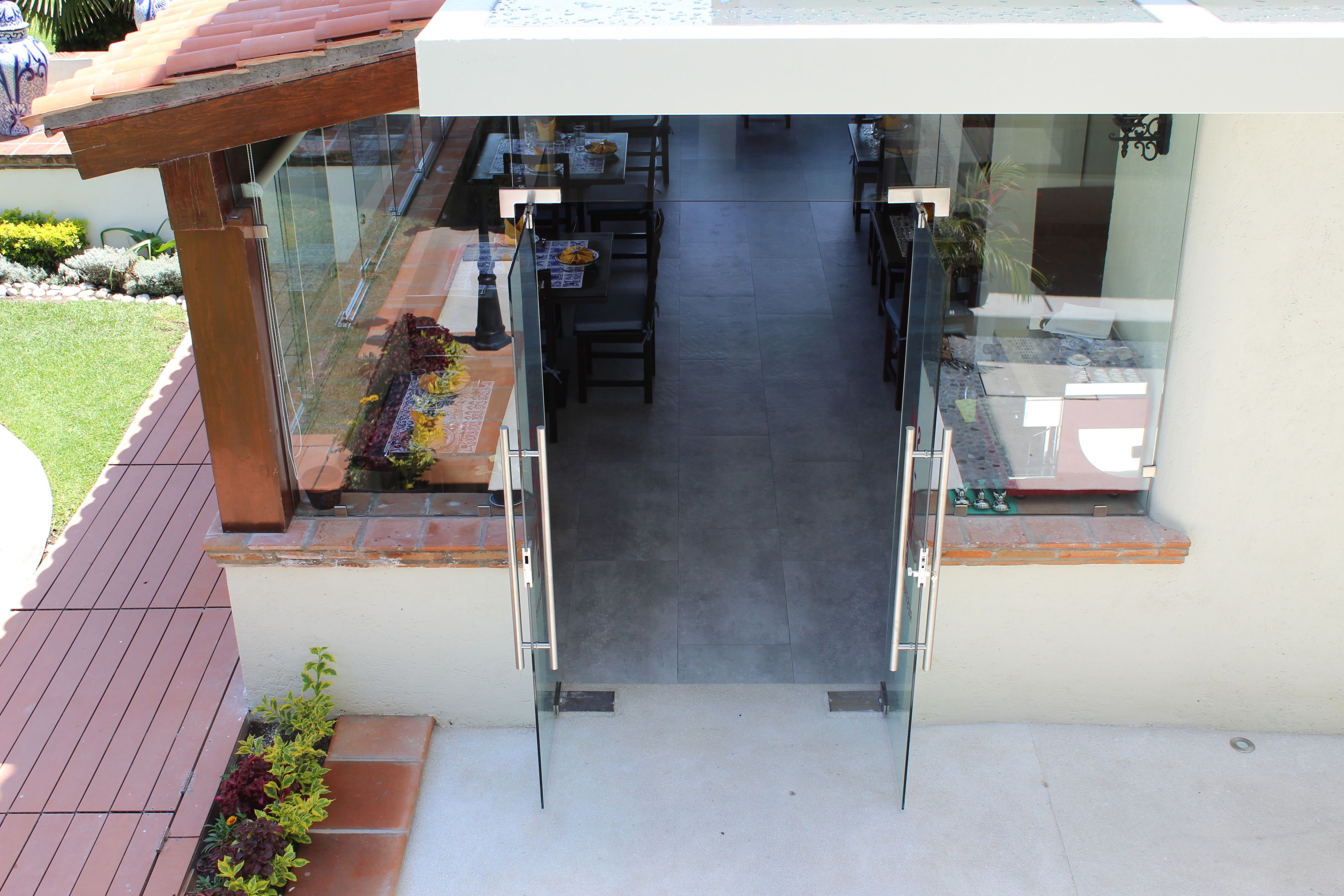 A modern outdoor seating area with glass railings and a wooden pergola.