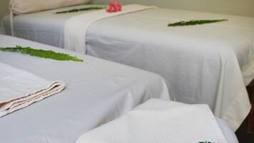 Two beds with crisp linens and fresh towels, complemented by a touch of natural decor.