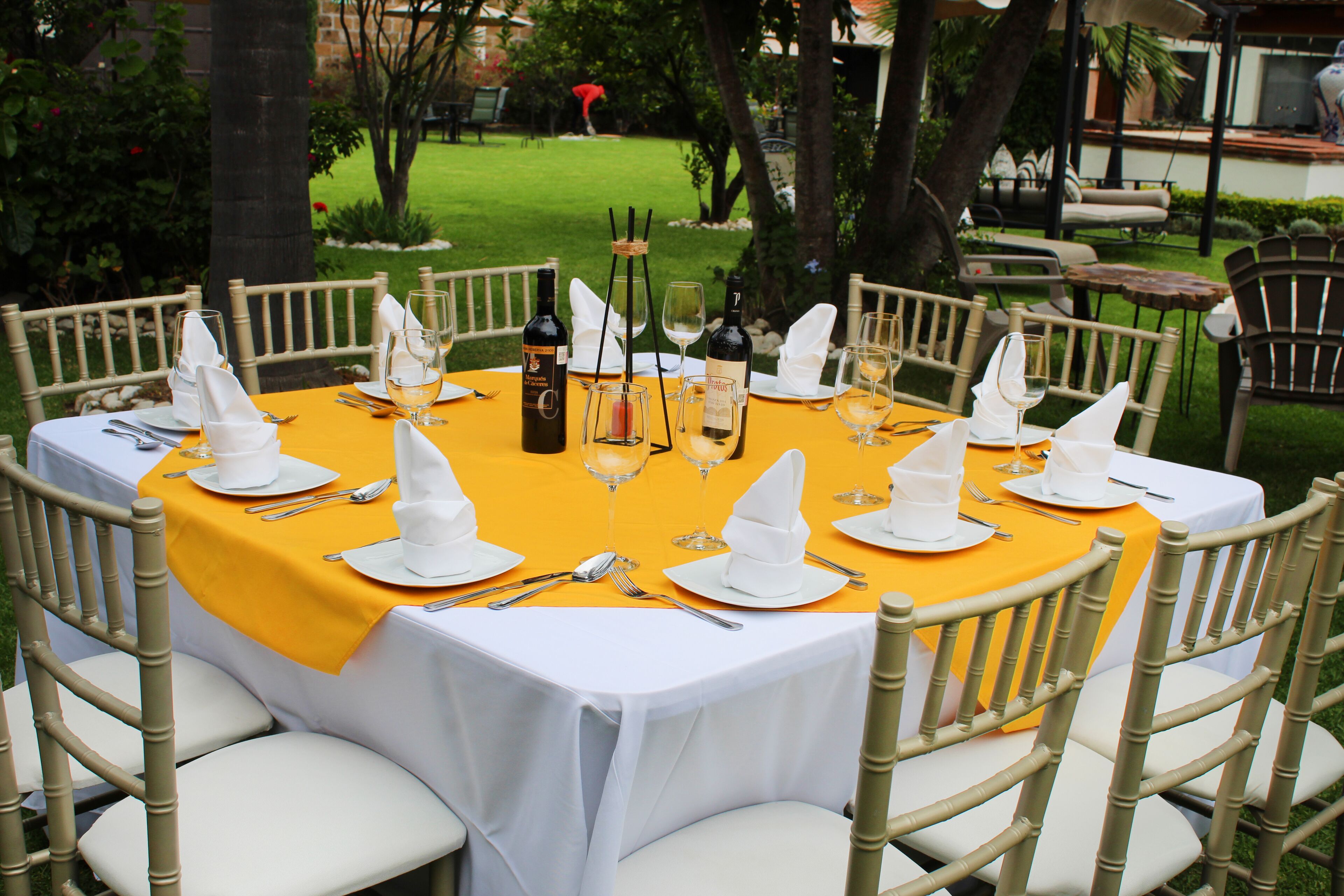 A round table set for a meal with white napkins, silverware, and wine glasses.