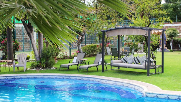 En swimmingpool med liggestole og en pavillon.