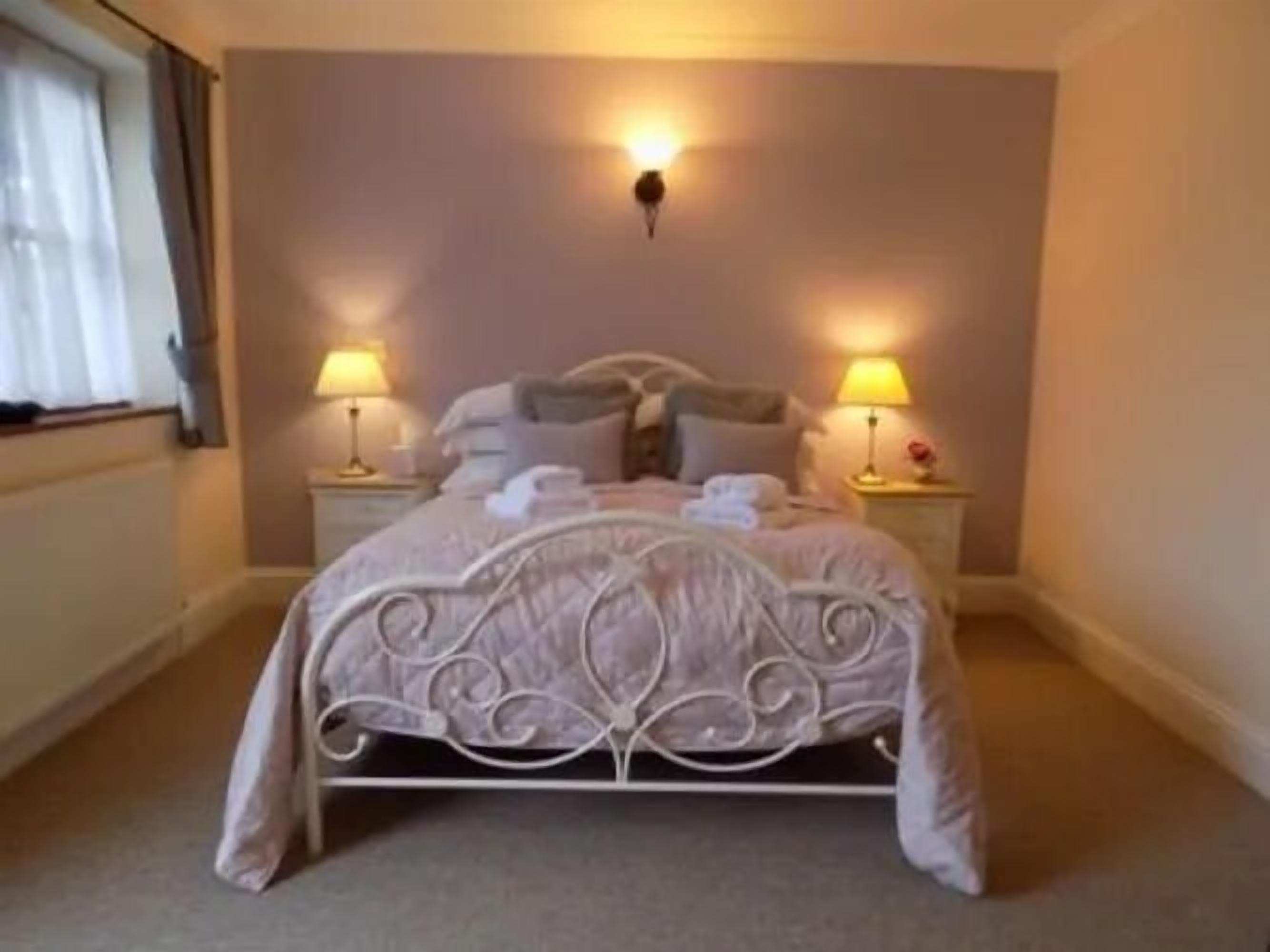 A bedroom with a bed, two bedside tables, and two lamps.