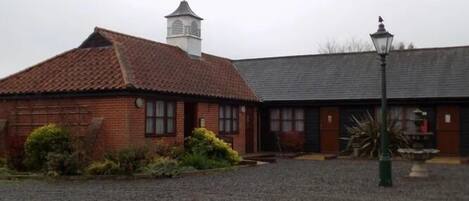 A building with a tiled roof, a small tower with a weather vane, and a lamp post.