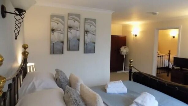 Habitació d'hotel amb un llit, una taula de nit, una làmpada i obra d'art a la paret.
