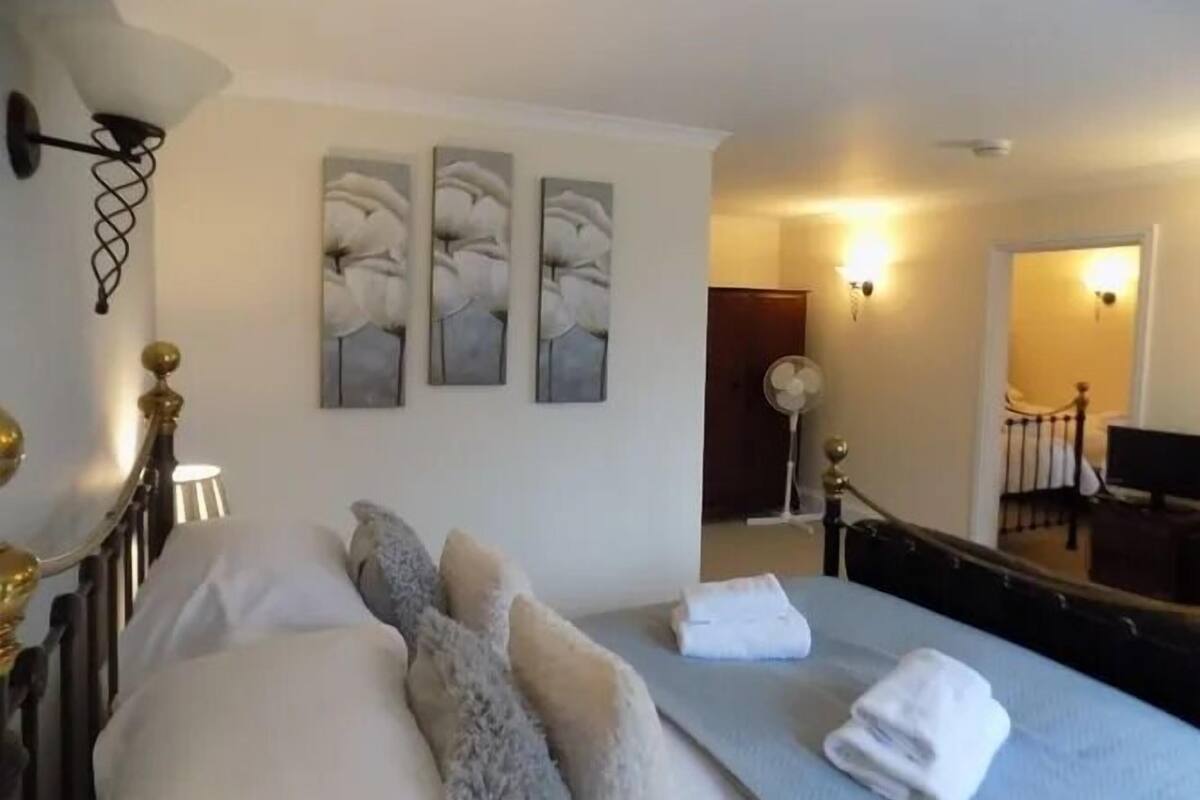 A hotel room with a bed, a bedside table, a lamp, and wall art.