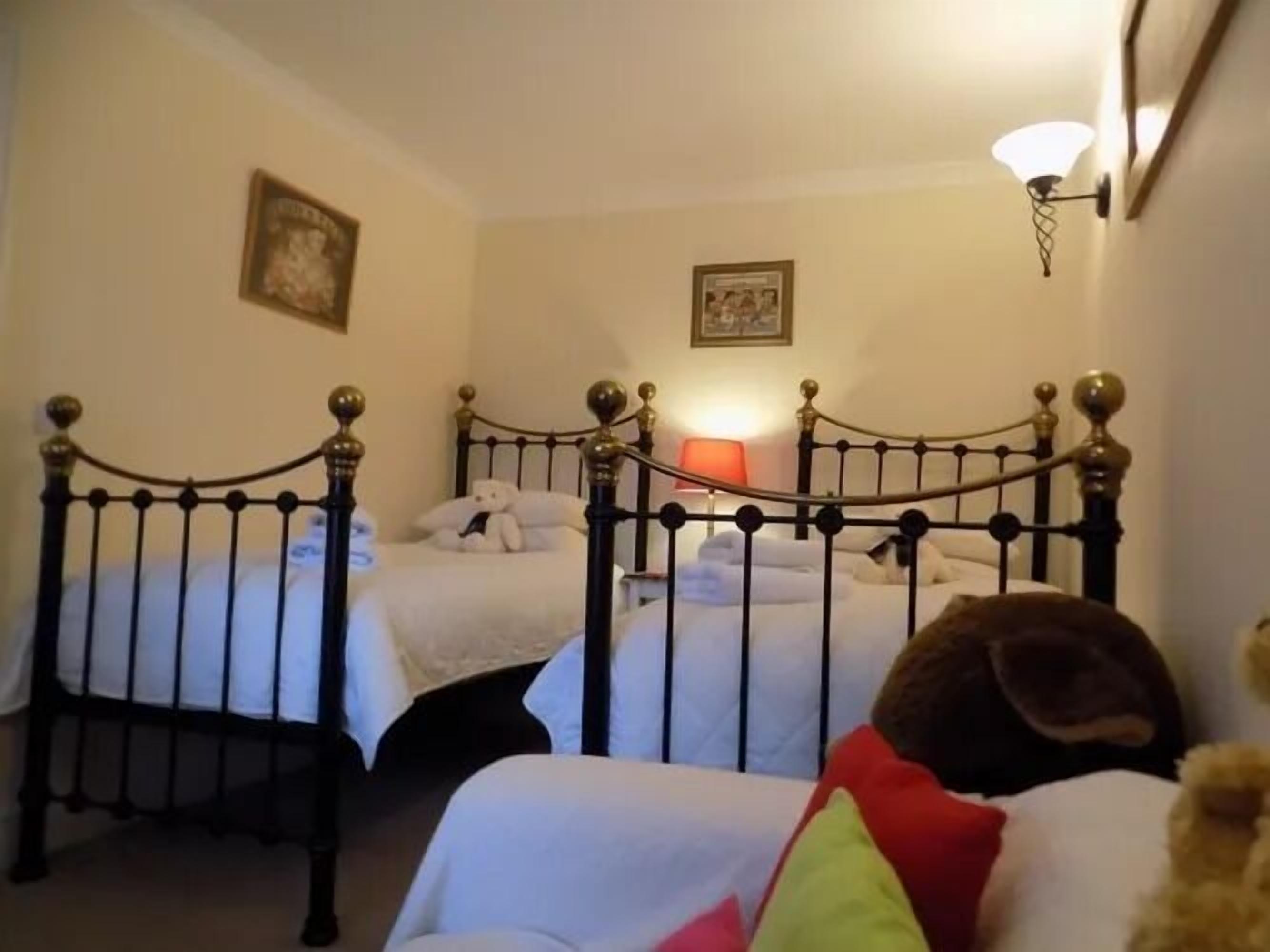 A hotel room with two beds, a wall-mounted lamp, and a framed picture.