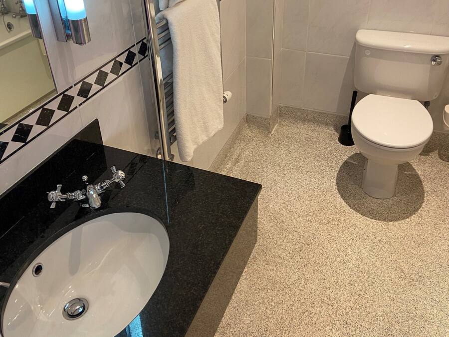 A modern bathroom with a black countertop sink, a white toilet, and a glass shower enclosure.