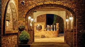 An arched brick entrance with hanging baskets and lanterns, leading to a gated area. - Loftsome Bridge Hotel (Selby)