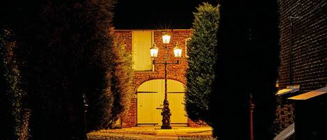 A brick building with a large arched entrance, two street lamps, and a fire hydrant in front.