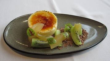 Un postre en un plato con diversas frutas y una cucharada de crema.