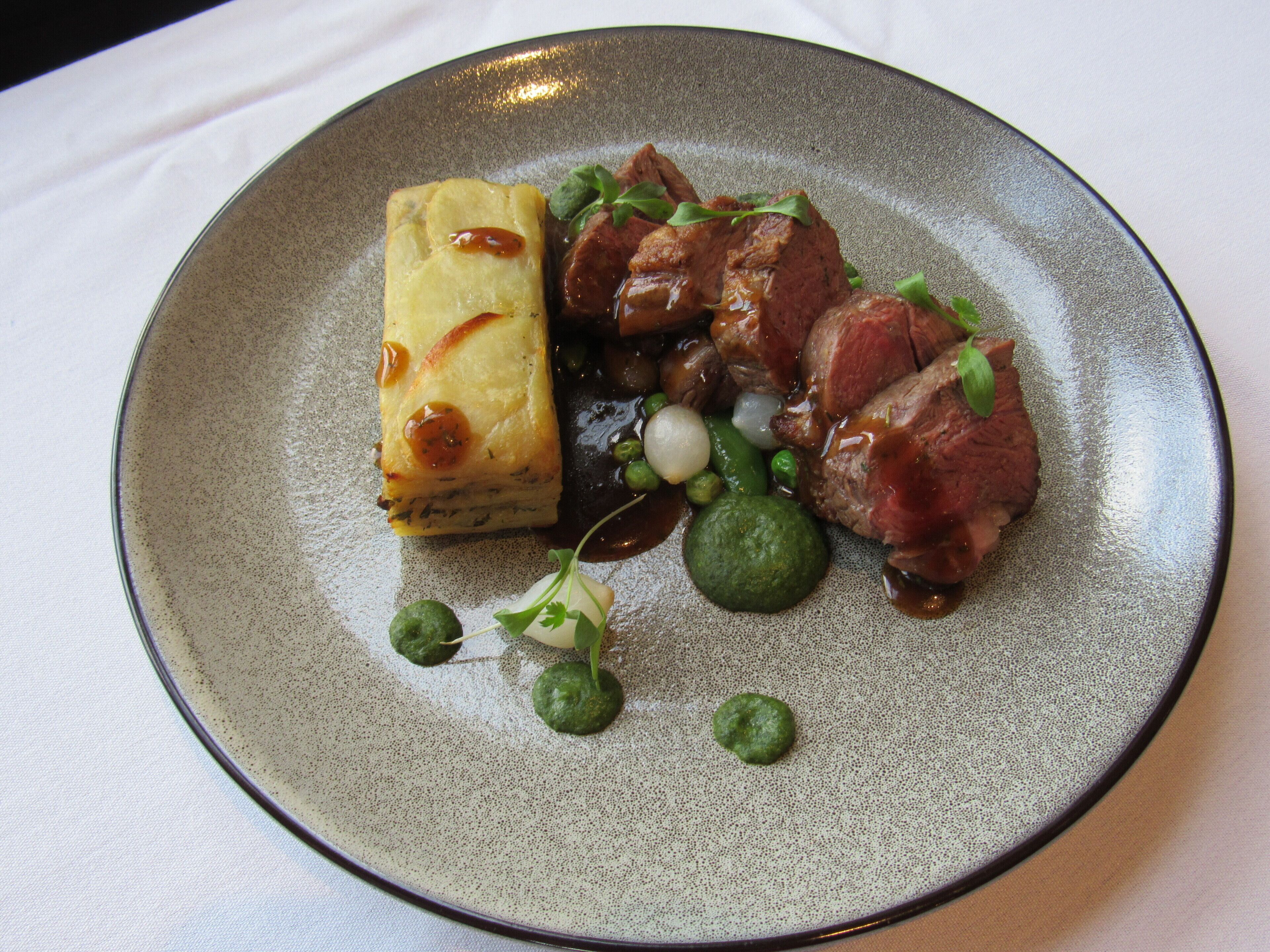 Un plato con carne, un vegetal verde y algo amarillo.