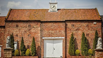 Un edificio de ladrillo con una torre del reloj, una puerta blanca y estatuas.