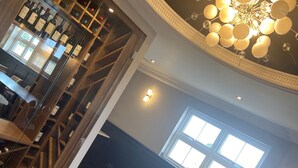 A restaurant interior with a wine rack, dining tables, chairs, and a chandelier. - Loftsome Bridge Hotel (Selby)