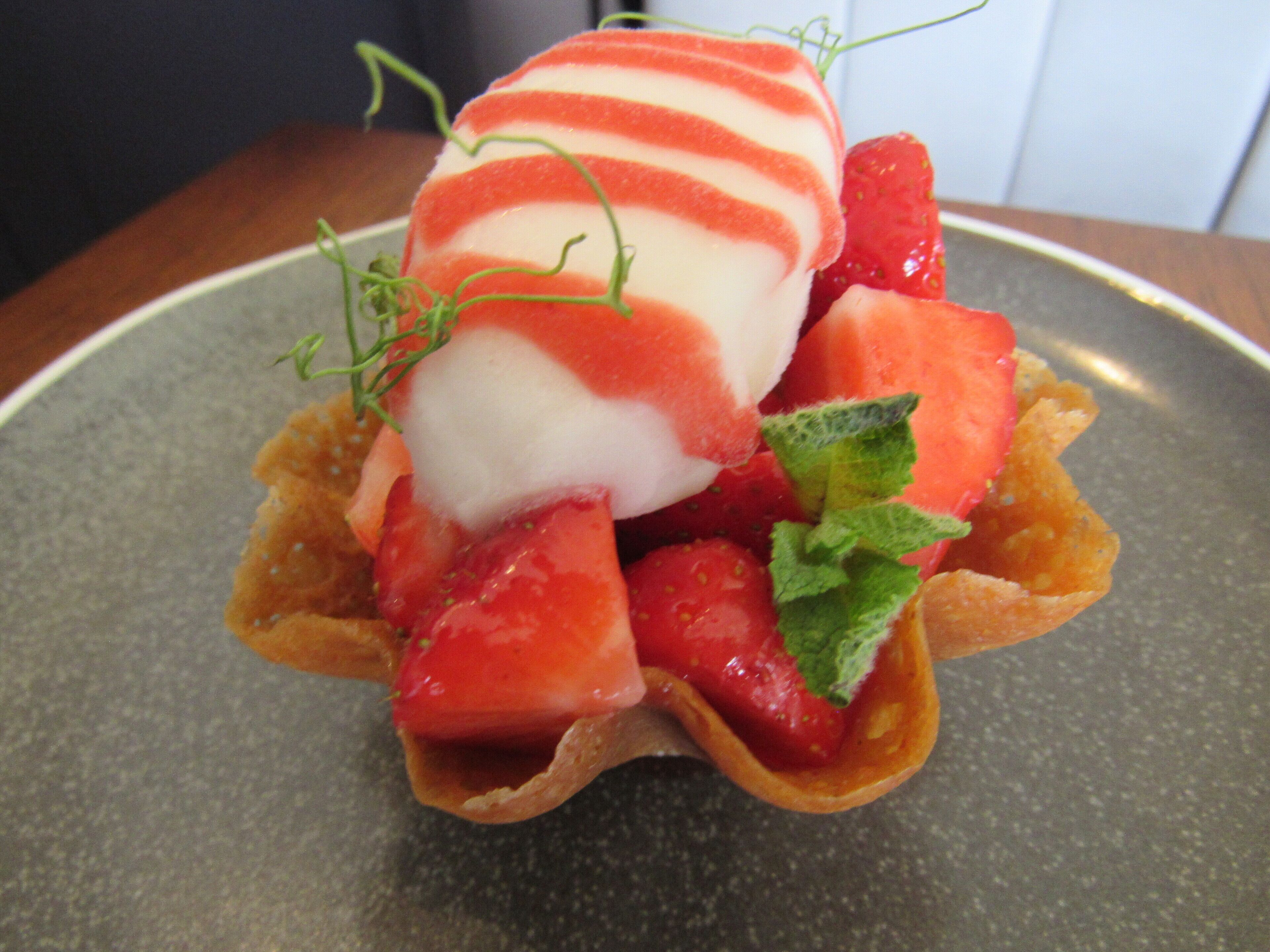 A dessert with strawberries and a scoop of ice cream on a plate.