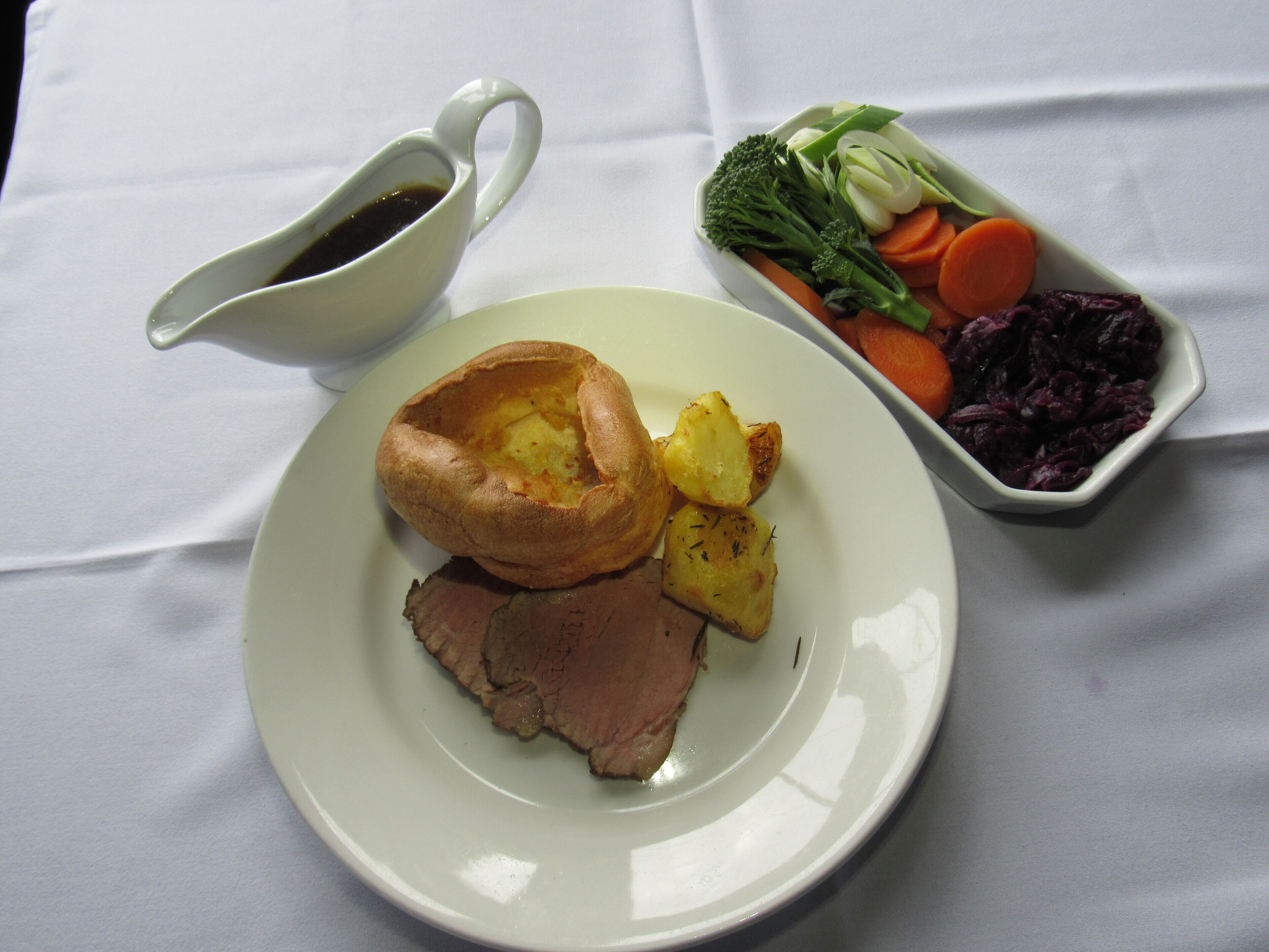 A plate with roast beef, Yorkshire pudding, and roasted potatoes.