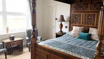 A four-poster bed with intricate woodwork, a bedside table with a lamp, and a window with curtains.