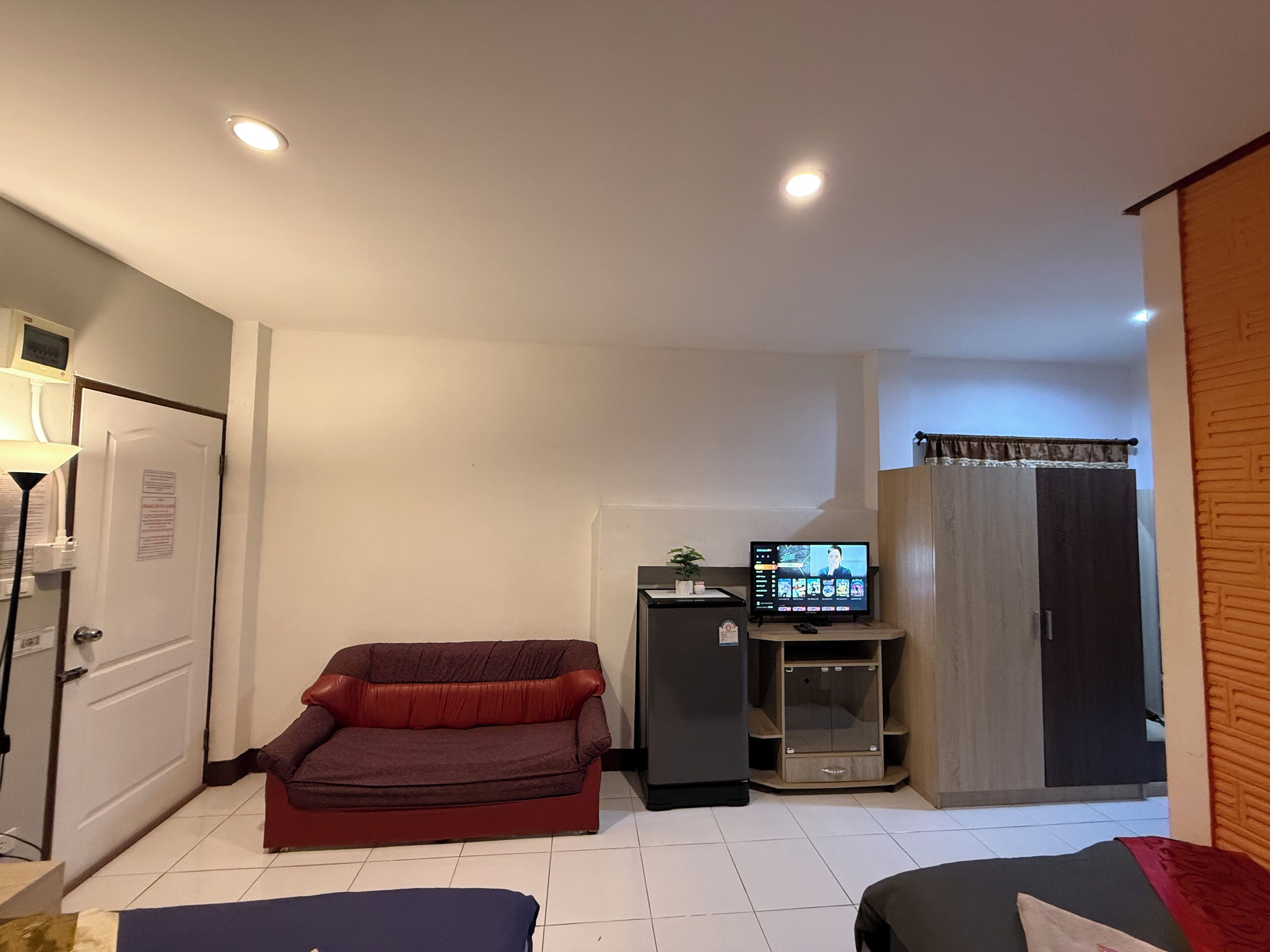 A compact living space with a sofa, a television, a refrigerator, and a wardrobe.