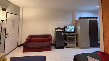 A compact living space with a sofa, a television, a refrigerator, and a wardrobe.