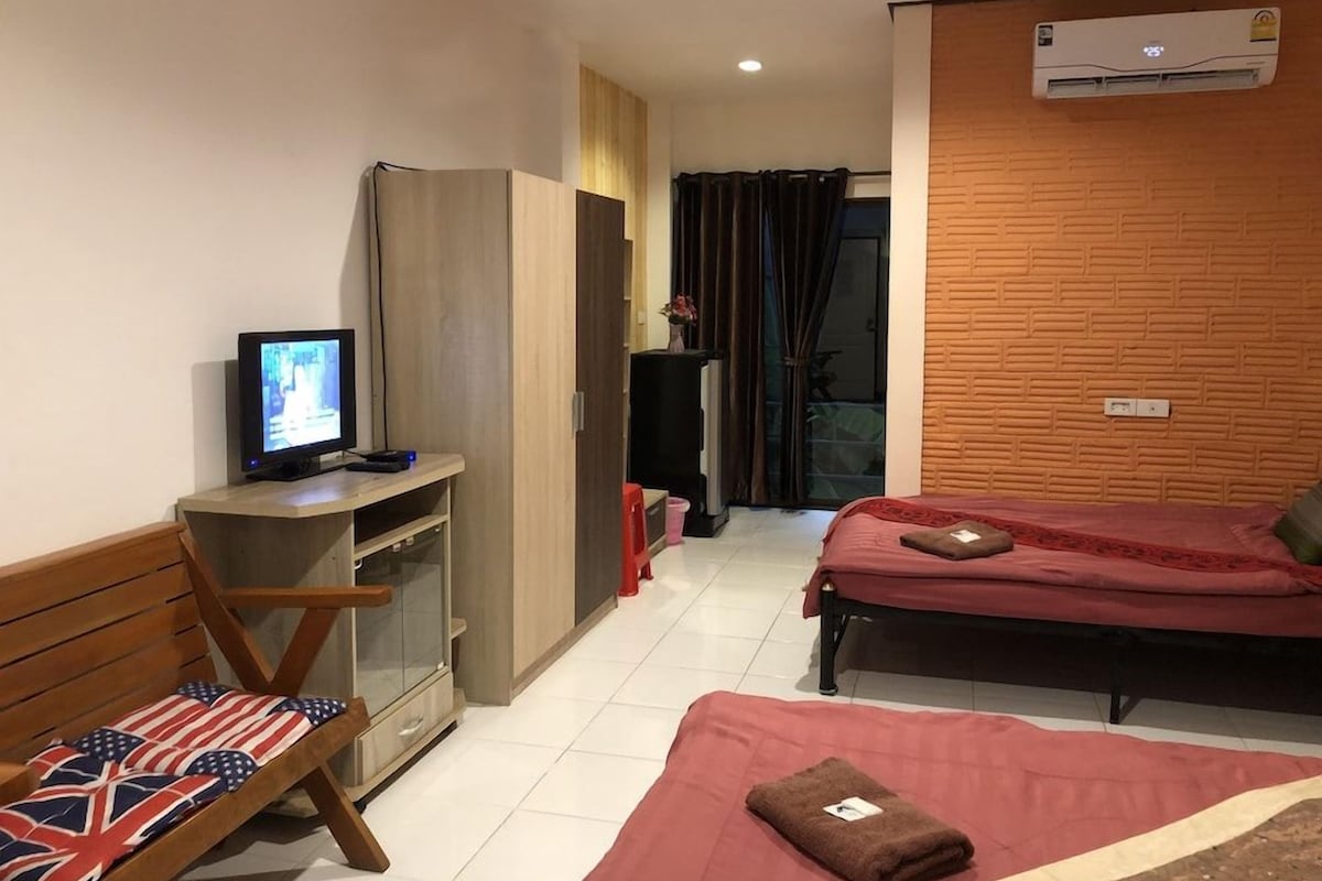 Quarto de hotel compacto com uma cama, escrivaninha com computador, cadeira e televisão.