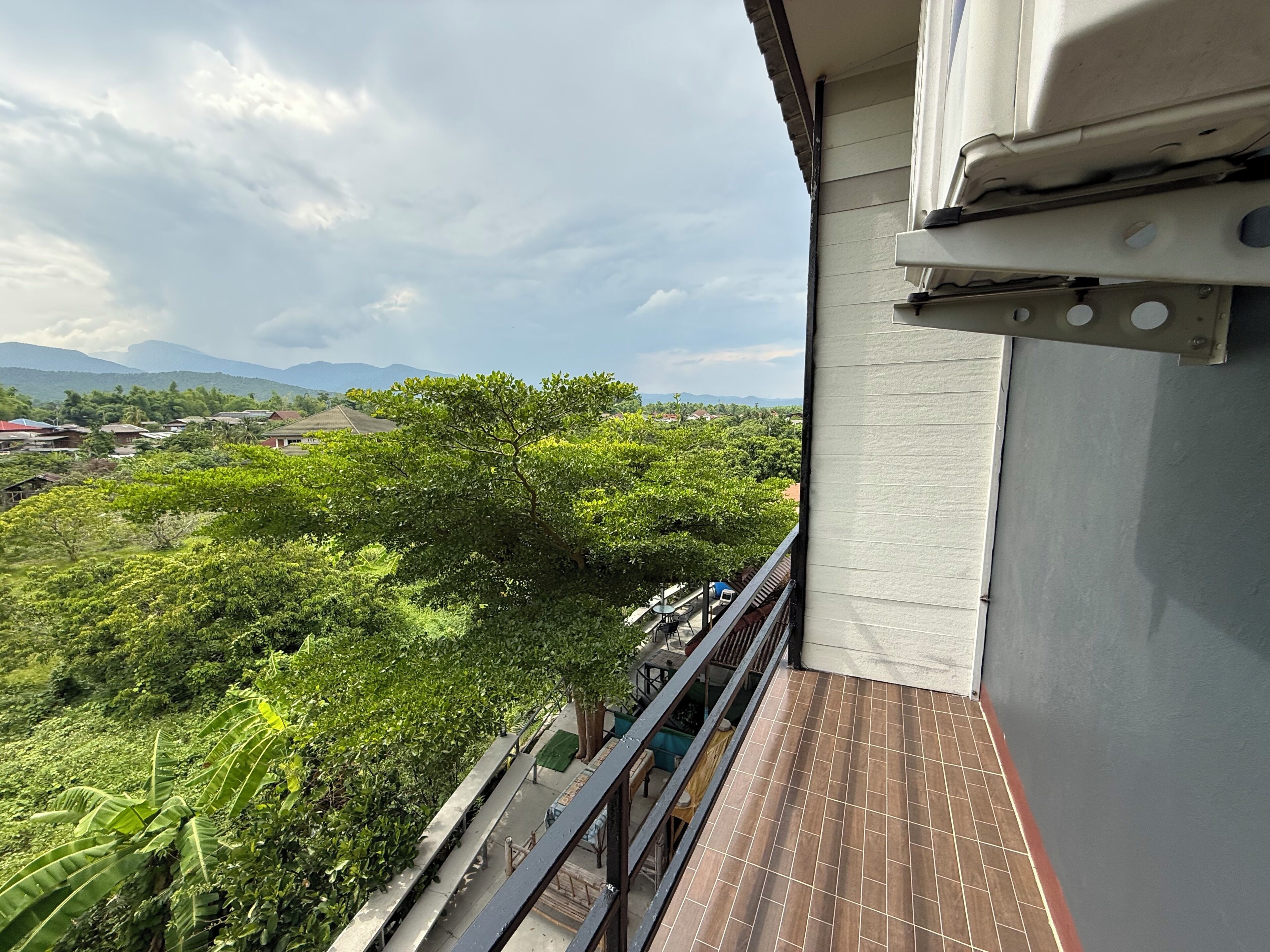 A balcony with a view of a lush green landscape and distant mountains.