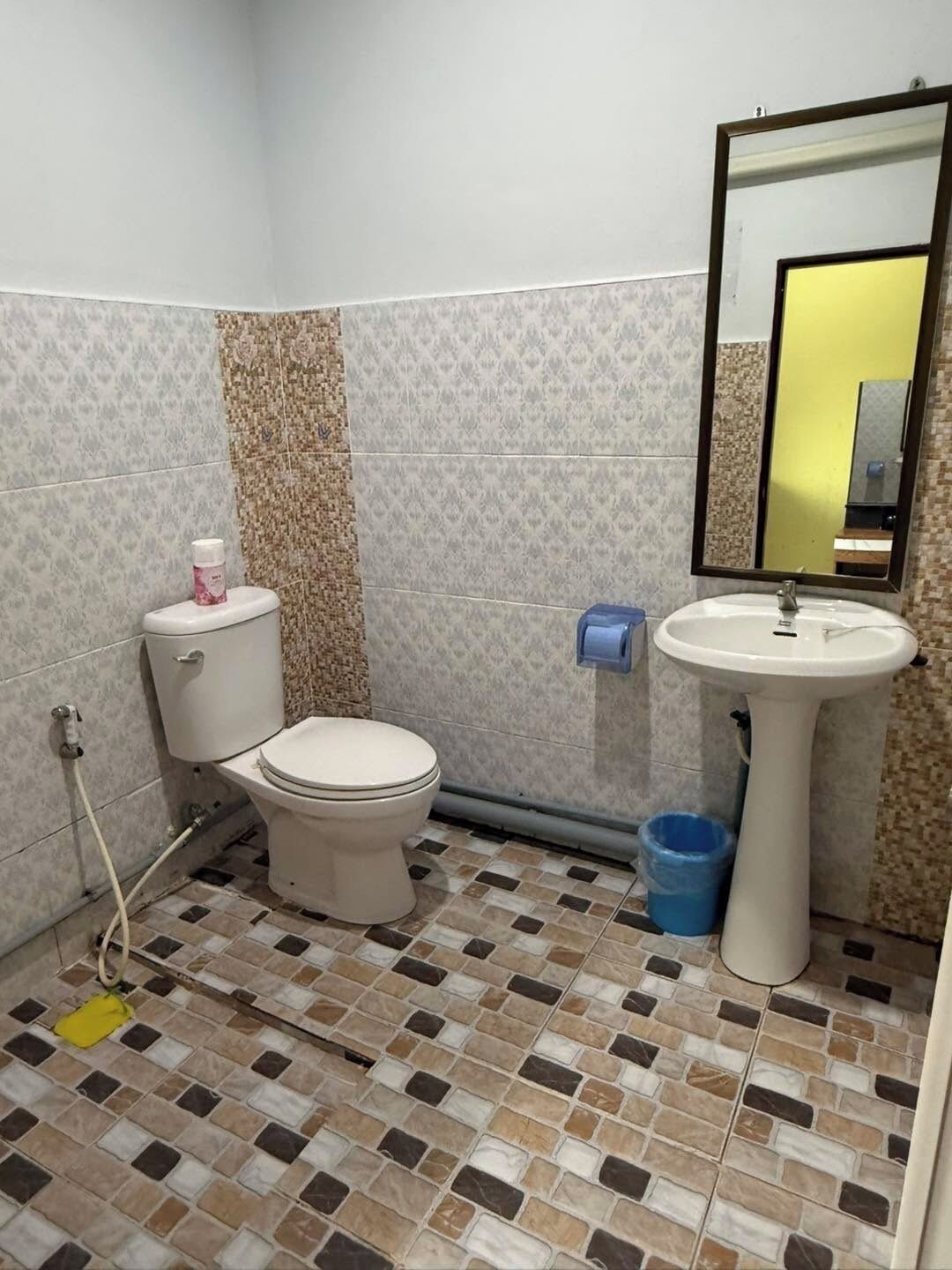 A bathroom with a toilet, sink, and mirror.