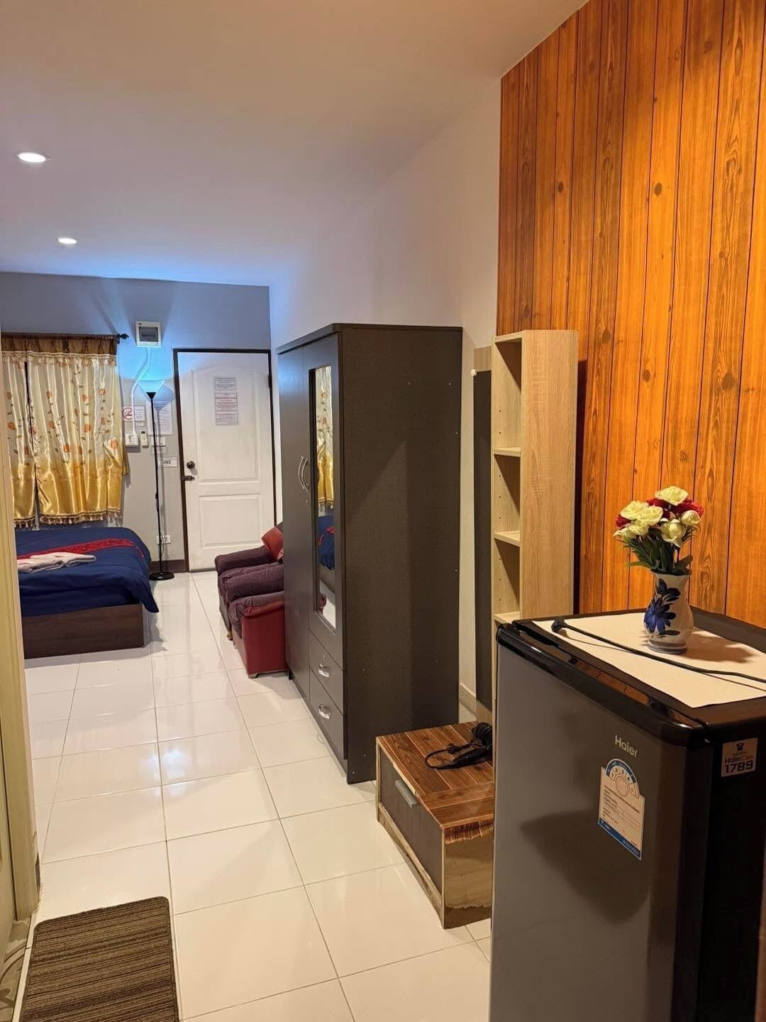 A hotel room with a bed, a wardrobe, a desk, and a wooden wall.