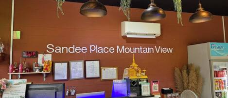 A reception desk with a sign reading 'Sande Place Mountain View,' a computer, framed certificates, and a small Buddha statue.