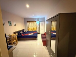 A hotel room with a bed, a desk, a chair, a wardrobe, and a door. - Sandee Place Mountain View Chomthong (Chom Thong)