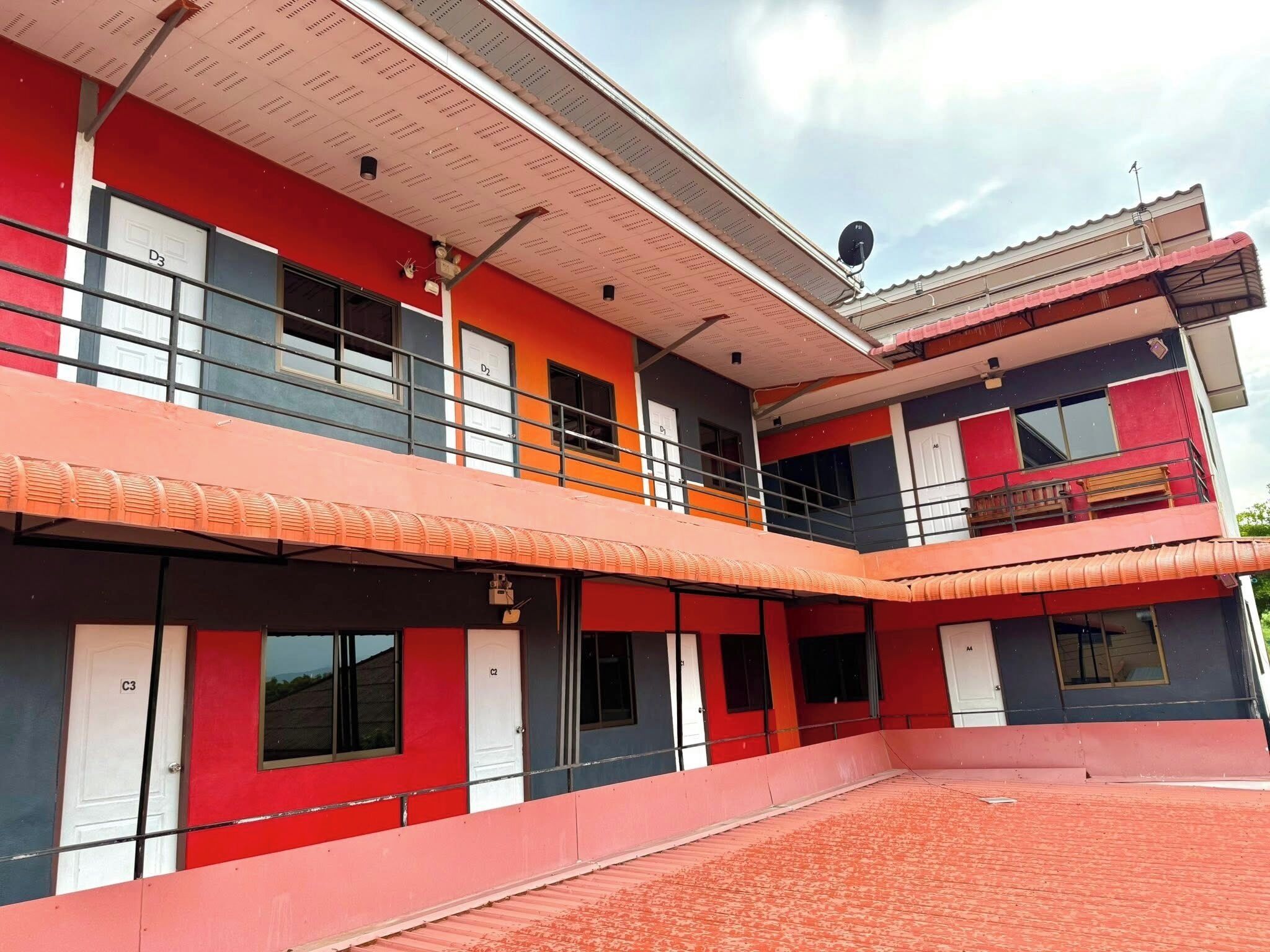 A multi-story building with balconies, a flat roof, and a satellite dish.