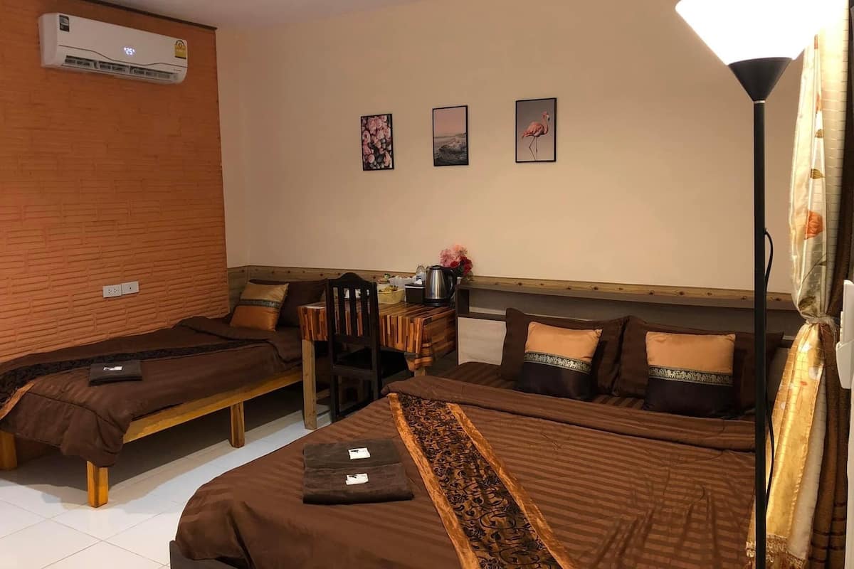 A hotel room with two single beds, a wooden headboard, a desk with a chair, and a lamp.