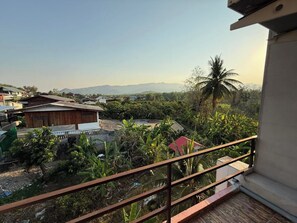 A residential area with houses, a balcony with a metal railing, and a view of a mountain range in the distance. - Sandee Place Mountain View Chomthong (Chom Thong)