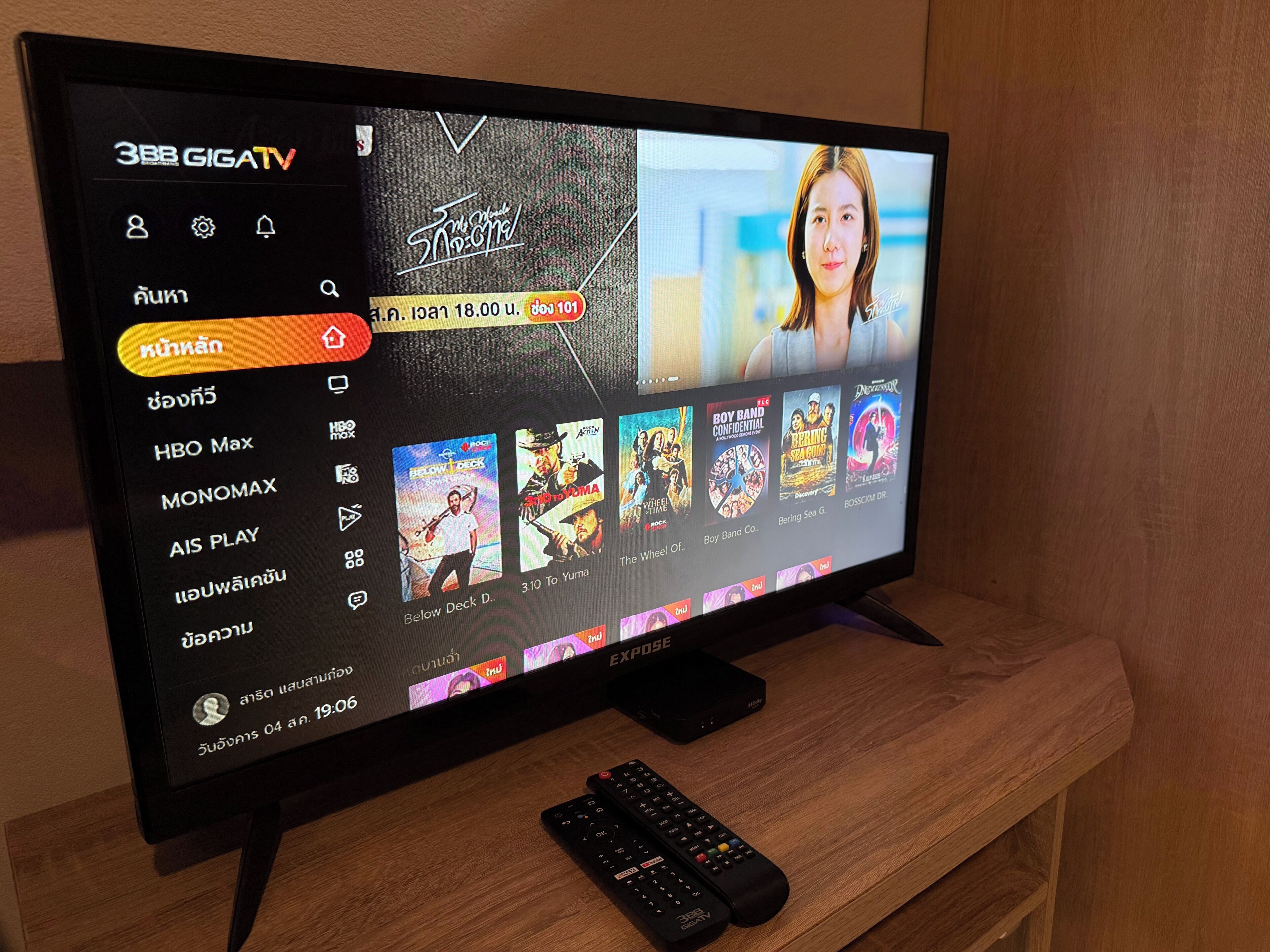 Un écran de télévision affichant l’interface d’un service de diffusion en continu, avec différentes options de contenu, et une télécommande posée sur une surface en bois.