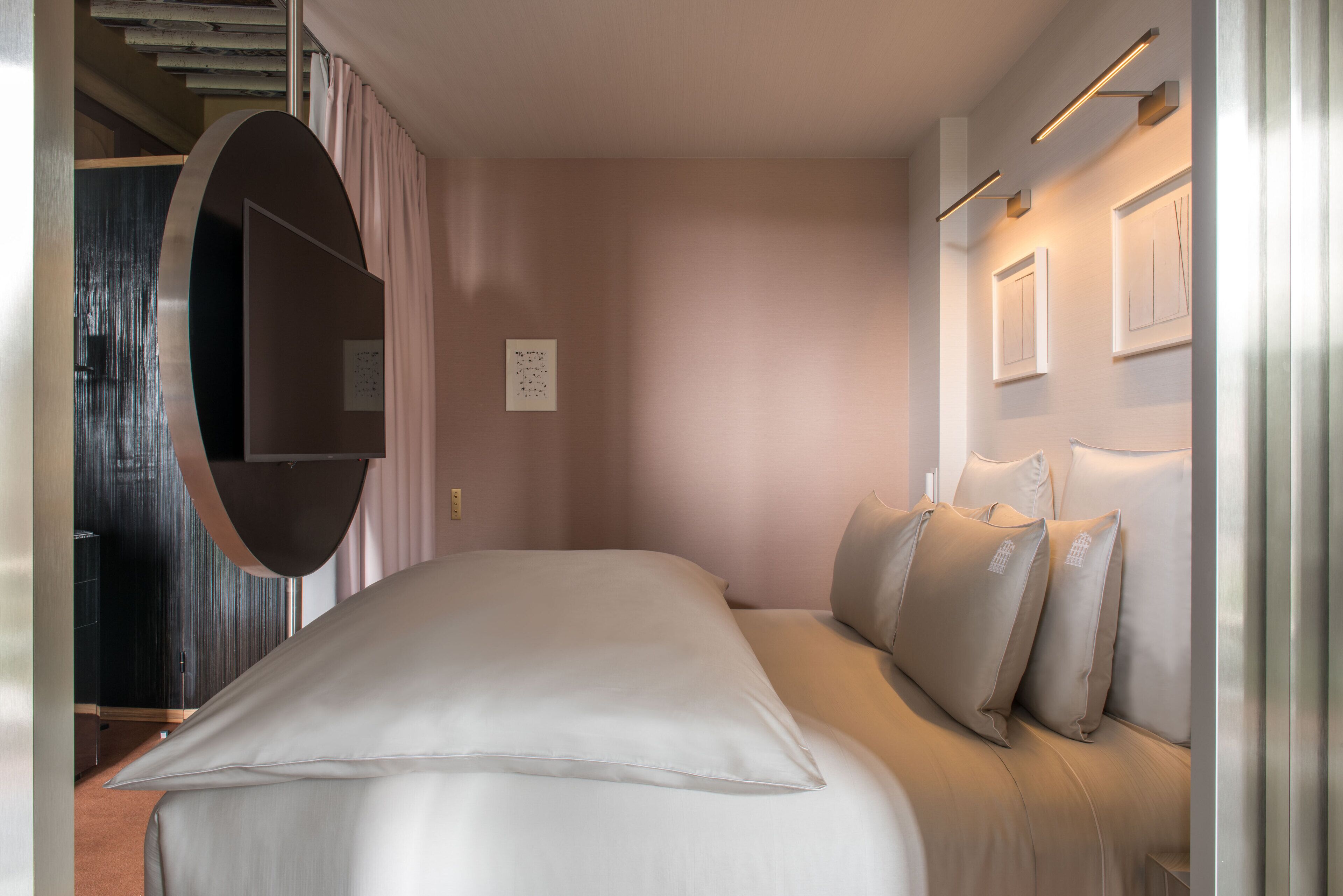 Un dormitorio moderno con una cama grande, un armario empotrado y una lámpara fijada a la pared.