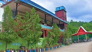 A building with a red brick tower, a blue roof, and a covered outdoor seating area. - Railroad Hotel Kalaw (Kalaw)