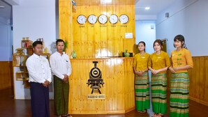 A reception desk with clocks indicating different time zones and a sign for the Railroad Hotel. - Railroad Hotel Kalaw (Kalaw)