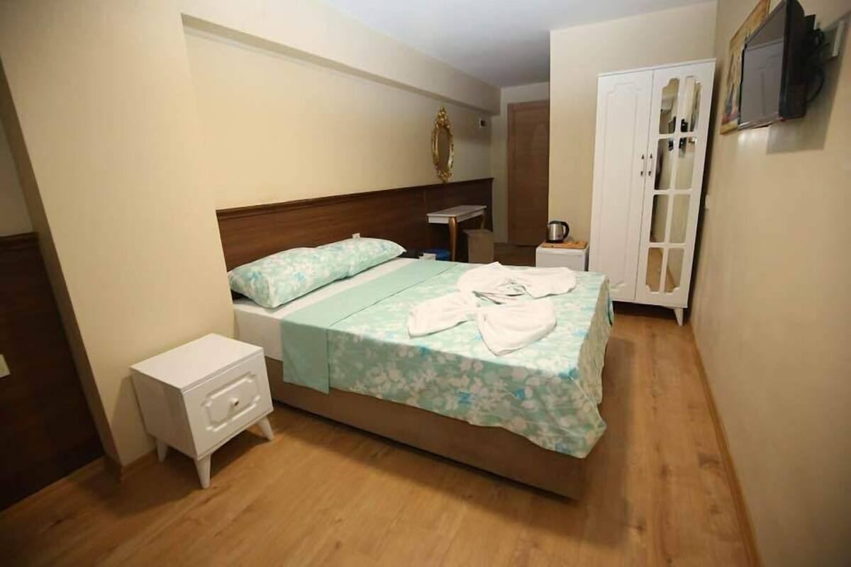 A bedroom with a bed, bedside table, nightstand, wardrobe, and a mirror.