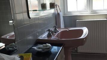 Un baño moderno con un lavabo rosa, un espejo y una ventana.