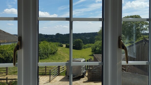 Blick durch ein Fenster mit Metallrahmen und Holzzaun.
