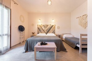 Un dormitorio con cama, mesitas de noche, una pequeña mesa y una decoración de macramé en la pared.