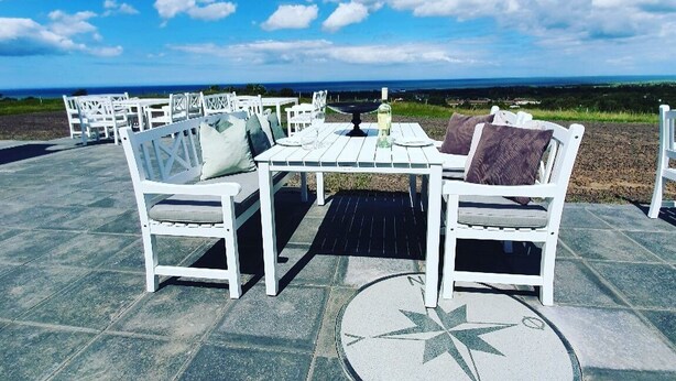 An outdoor dining area with white furniture and a compass design on the floor, overlooking a scenic landscape. - Hotel Nor - Badehotellet (Fjerritslev)