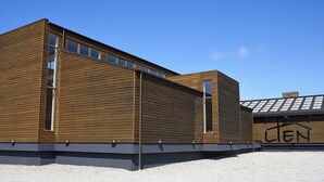A modern building with horizontal wooden panels and a flat roof. - Hotel Nor - Badehotellet (Fjerritslev)