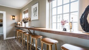 A kitchen with a wooden bar counter, bar stools, and a large window with a view. - Hotel Nor - Badehotellet (Fjerritslev)