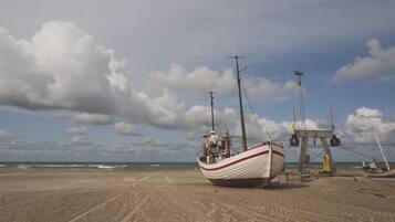 Guests can enjoy stunning ocean views from the beach, where a fishing boat is anchored nearby.