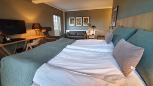 A hotel room with a large bed, a desk with a computer, a TV, and a window with blinds. - Hotel Nor - Badehotellet (Fjerritslev)
