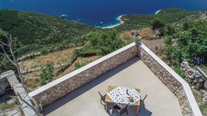 A terrace with a table and chairs, overlooking a coastal landscape with a clear view of the sea and a small beach. - 1 bedroom nice home in Lubenice (Lubenice)