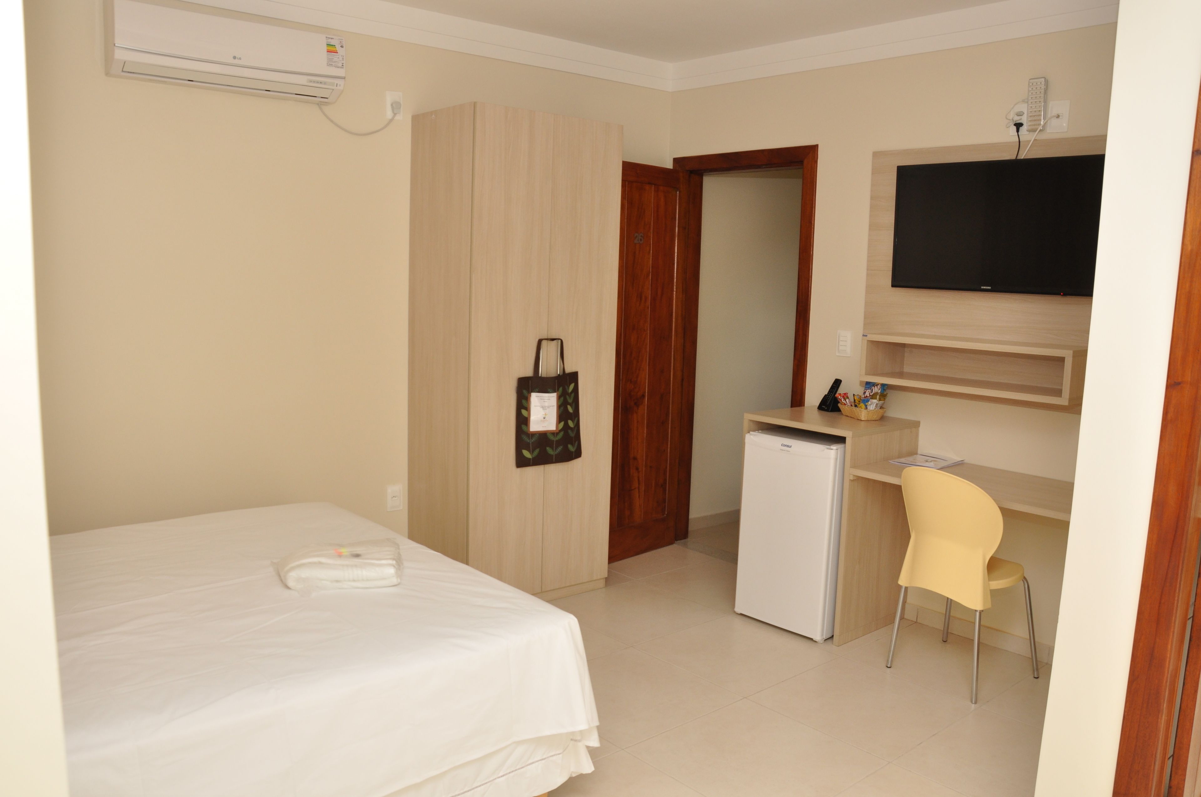 Una habitación de hotel con cama, escritorio, silla, televisor y minibar.