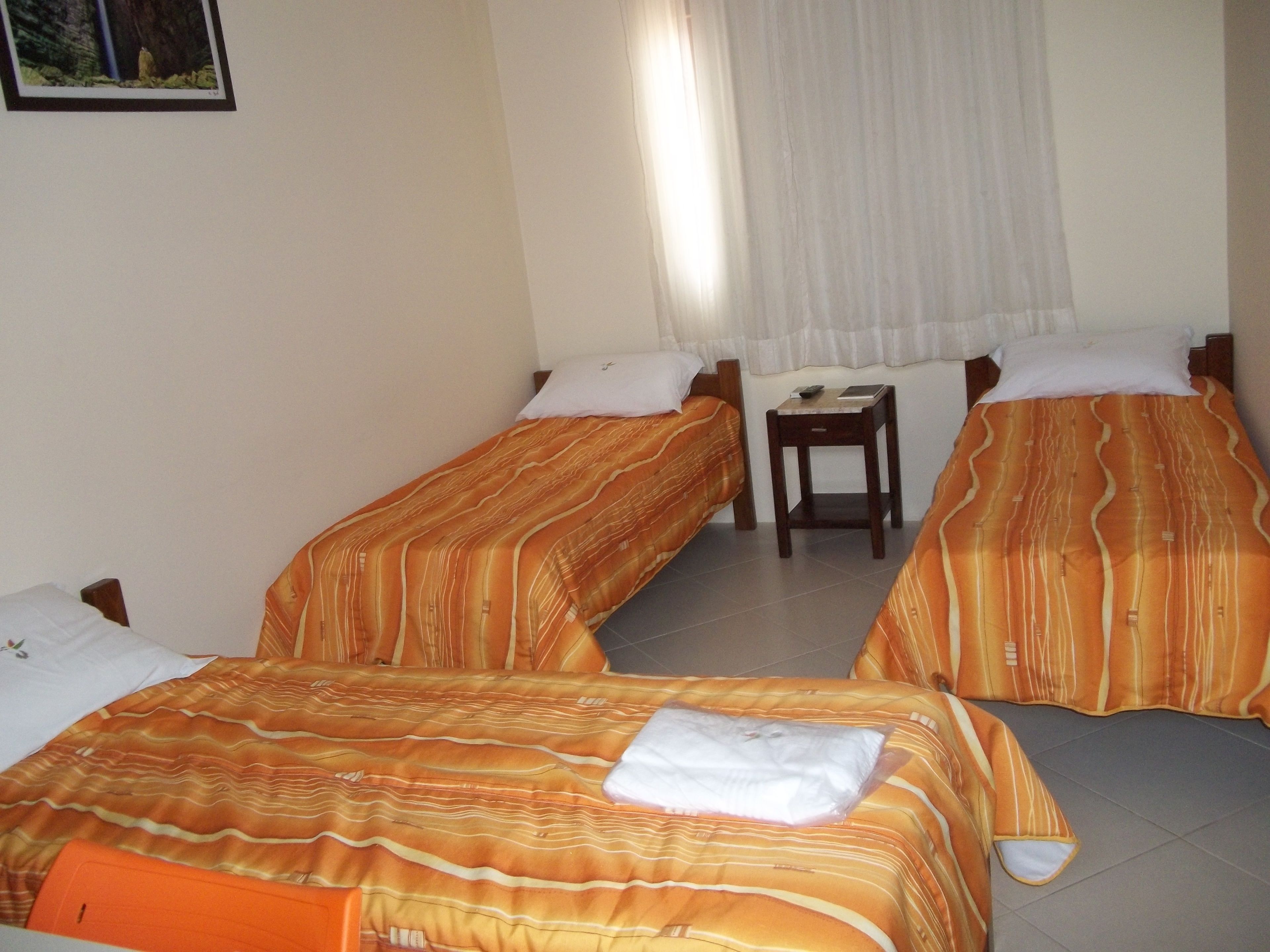Una habitación de hotel con dos camas individuales, una mesita de madera y una ventana con cortinas.