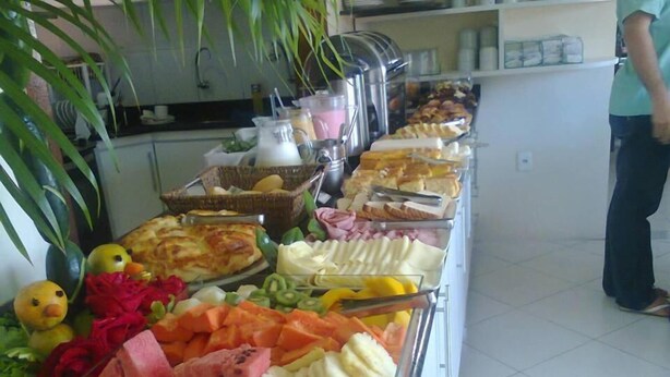 A buffet with various food items including fruits, vegetables, and pastries. - Beija Flor Hotel (Ipiau)