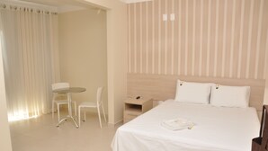 A hotel room with a bed, a desk, a chair, and a small table. - Beija Flor Hotel (Ipiau)